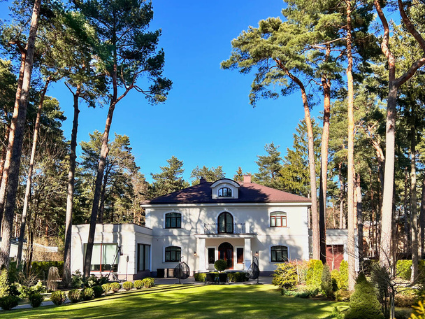 LATVIA, RIGA, APRIL, 2022 - Private residence with a large green lawn in a beautiful garden surrounded by tall pines in Mezaparks, Riga, Latvia - Foto, imagen