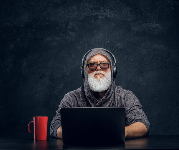 Сучасний літній хакер з чашкою і ноутбуком, що сидить за столом
 - Фото, зображення