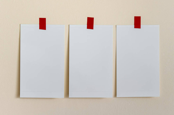 Plantilla de burla con tres tarjetas blancas en blanco adjuntas con cintas rojas a la pared amarilla. - Foto, imagen