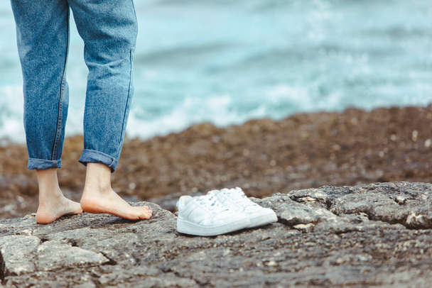 жінка ходить босоніж на узбережжі, тримаючи в руках біле взуття. літні канікули. природоохоронний союз
 - Фото, зображення