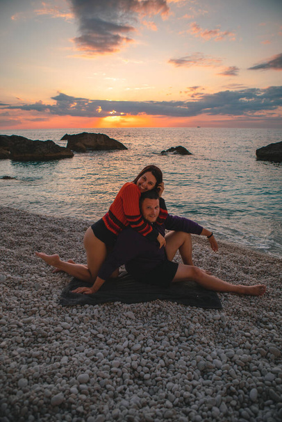 ζευγάρι εραστές στην παραλία απολαμβάνοντας το χρόνο μαζί και το ηλιοβασίλεμα πάνω από τη θάλασσα Ελλάδα διακοπές Λευκάδα νησί - Φωτογραφία, εικόνα