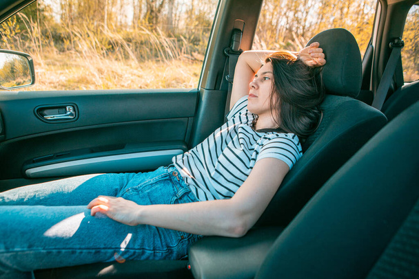 γυναίκα κάθεται στο αυτοκίνητο στο κάθισμα του συνοδηγού αντίγραφο χώρο ηλιόλουστο βράδυ - Φωτογραφία, εικόνα