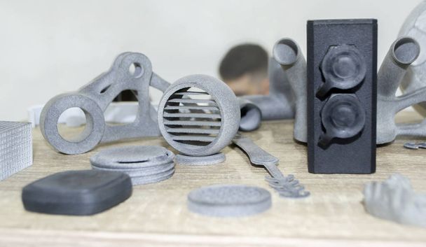 Molti modelli stampati su stampante 3D. Stampante 3D stampata con oggetti grigi e neri. - Foto, immagini
