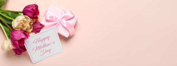 Cartão de saudação para o Dia das Mães, presente e belas tulipas em fundo rosa com espaço para texto - Foto, Imagem