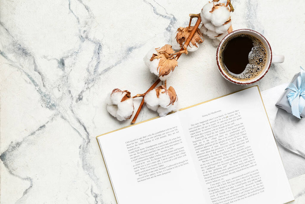 Taza de café, libro abierto y flores de algodón sobre fondo claro - Foto, imagen