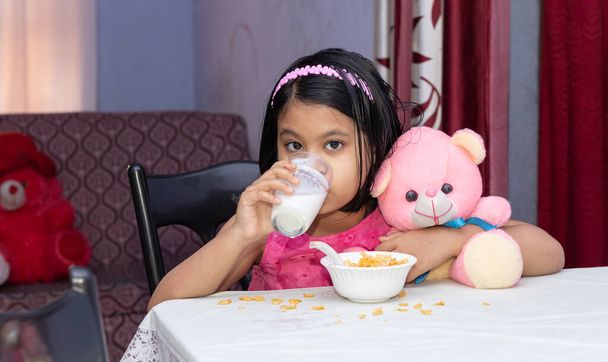 Una ragazza indiana che beve latte con cereali guardando la macchina fotografica - Foto, immagini