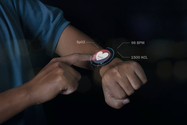 Człowiek korzystający z technologii inteligentnego zegarka sprawdza tętno ikoną aplikacji zdrowia na ekranie. Holograficzny interfejs użytkownika ikony. Futurystyczna technologia inteligentnego zegarka. Koncepcja opieki zdrowotnej. - Zdjęcie, obraz