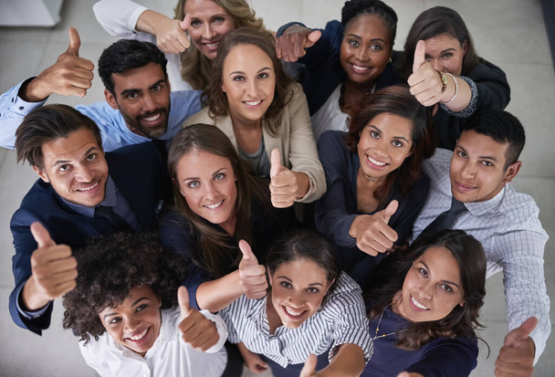 This team is all about positive attitudes. High angle portrait of a group of coworkers showing a thumbs up in the office. - Foto, imagen