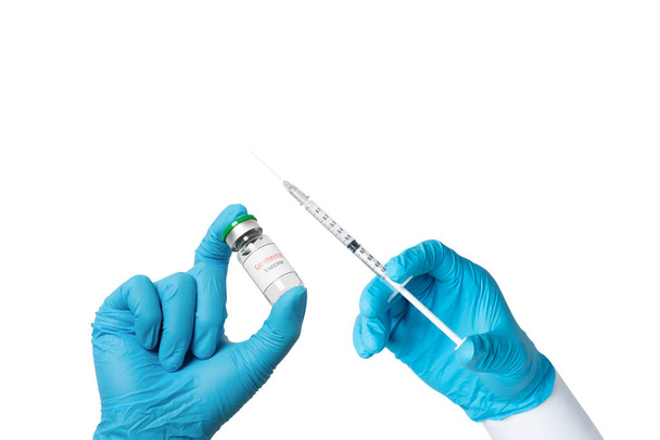 Hand wearing blue glove holding syringe and Coronavirus Vaccine in glass bottle. Syringe and Vaccine in hand. Vaccination, medical treatment and medicare concept. isolated on white background. - Photo, Image