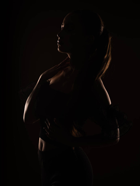 Attractive silhouette of a girl posing in a studio while standing - Foto, Imagem