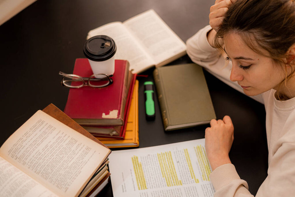 Όμορφο κορίτσι διαβάζει σε ένα γραφείο, ενώ έχουν πρόβλημα με τις σπουδές της για το κολέγιο - Φωτογραφία, εικόνα