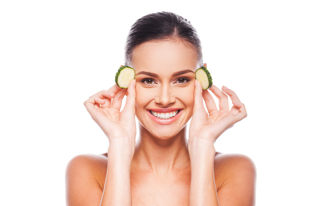 Young shirtless woman holding slices of cucumber - Photo, Image