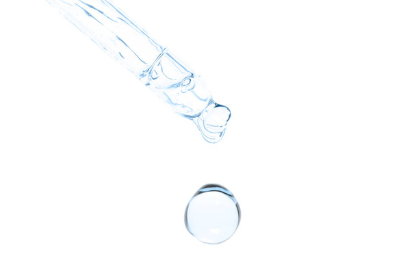 macro van pipet met vloeistof en druppel op witte achtergrond - Foto, afbeelding