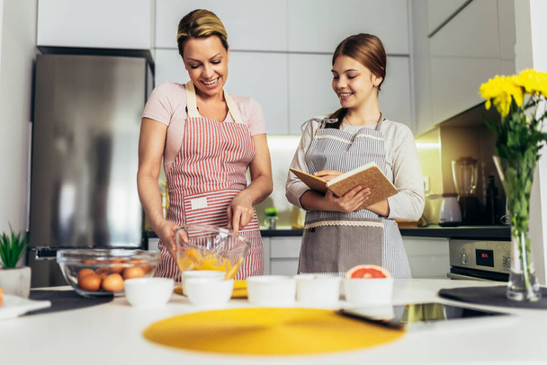 Lächelnde Mutter und Tochter kochen gemeinsam in der Küche - Foto, Bild