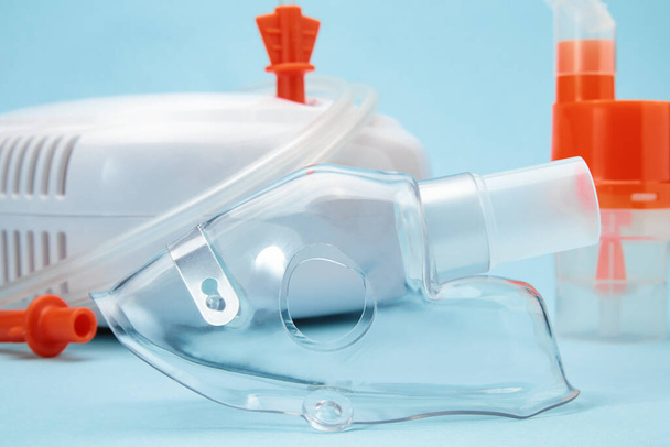 Gros plan du masque respiratoire pour nébuliseur compresseur sur fond bleu. Matériel médical d'inhalothérapie pour l'asthme et les maladies respiratoires. - Photo, image