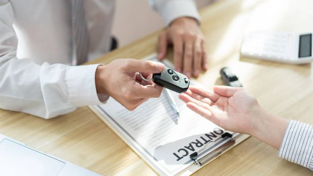 Ασφαλιστική έννοια του αυτοκινήτου αντιπροσωπείας δίνοντας ένα κλειδί αυτοκινήτου για τον πελάτη του μετά την υπογραφή της σύμβασης . - Φωτογραφία, εικόνα