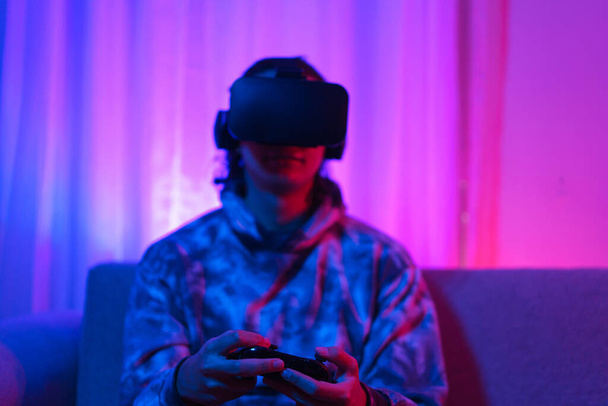 Metaverse technology concept, Man wear VR goggles and use joystick to play sport games in metaverse. - Photo, Image