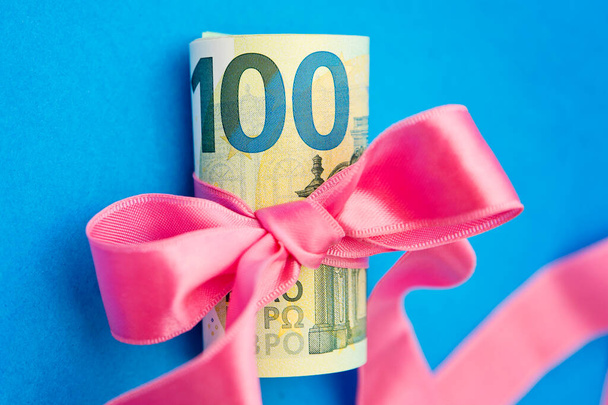 Concept, money as a gift, win or bonus. Takes or gives pile of 100 dollar bills tied with red ribbon with bow. - Photo, Image