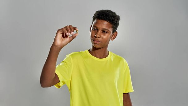 Black boy holding and looking at medical pill - Photo, Image