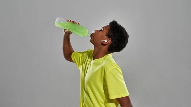 Athletic black boy drink sport drink from bottle - Fotó, kép