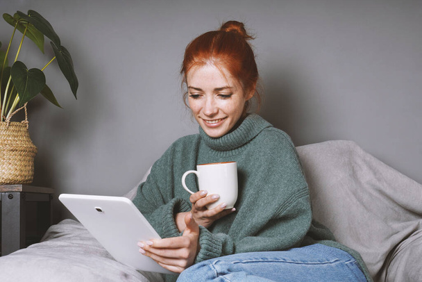 woman relaxing at home using tablet computer for entertainment or communication and drinking coffee - Foto, Imagem