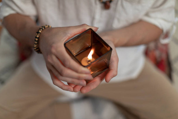 Κοντινό πλάνο ενός άνδρα που κρατάει ένα κερί στα χέρια του πριν την καθημερινή του συνεδρία διαλογισμού. - Φωτογραφία, εικόνα
