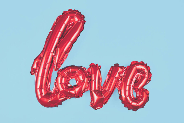 Ballon rouge brillant formant le mot "amour" sur fond bleu - Photo, image