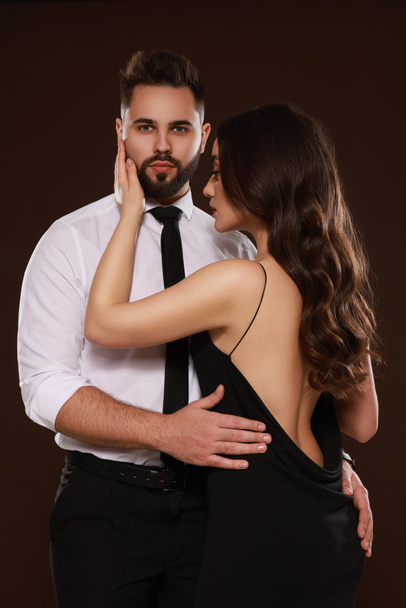 Handsome bearded man with sexy lady on dark brown background - Zdjęcie, obraz