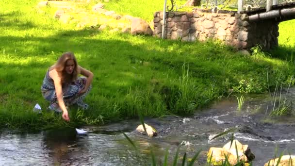 Bella donna incinta lasciare che la nave di carta galleggiare sull'acqua del fiume
 - Filmati, video