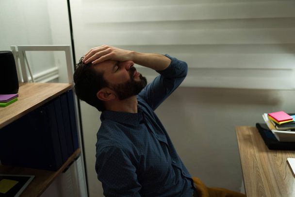 Перероблена концепція. стресові кавказькі почуття дуже втомлені і страждають від головного болю під час роботи пізно вдома
 - Фото, зображення