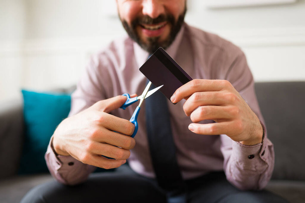 Primer plano de un hombre rico feliz cortando con tijeras su tarjeta de crédito después de alcanzar la libertad financiera - Foto, imagen