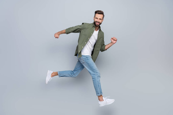 Full length body size view of attractive cheerful successful guy jumping running motion isolated over grey pastel color background - Фото, изображение
