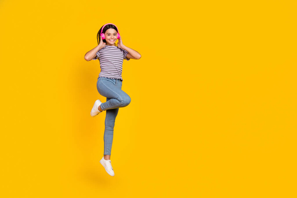 Full length photo of young cheerful lady listen radio earphones jump mp3 melody isolated over yellow color background - Foto, Imagem