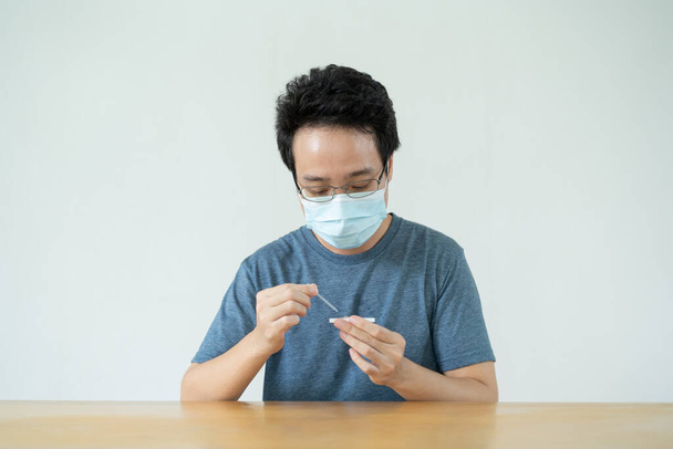 Asian young man having a swab COVID-19 or Coronavirus 2019 antigen - ag self test at home. Antigen or ag test use for 2019 SARS nCoV infection test. - 写真・画像