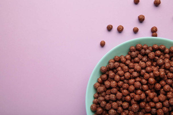Chocolate cereal corn balls in a blue bowl on a purple background. Top view. - Photo, Image