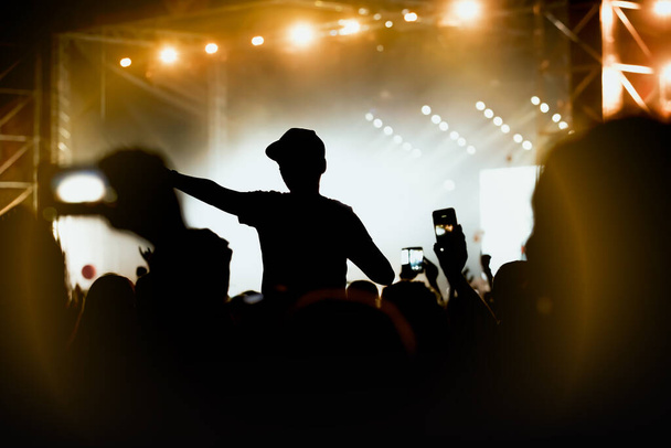 İzleyiciler sahnenin altına. Yaz festivali rock konserinde elini kaldıran adam. - Fotoğraf, Görsel
