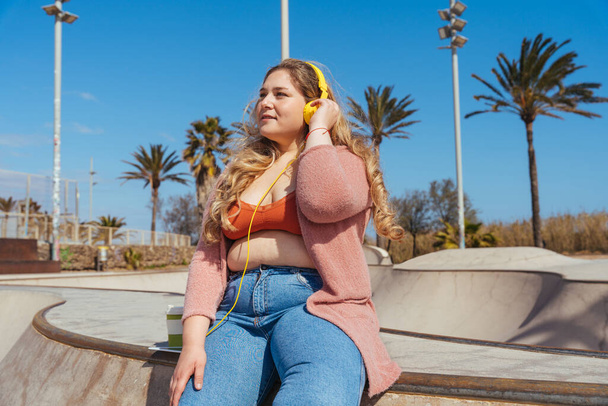 Beautiful and cheerful plus size young woman outdoors - Pretty overweight curvy female, concepts about femininity, women power, female emancipation, body positivity and body acceptance - Photo, image