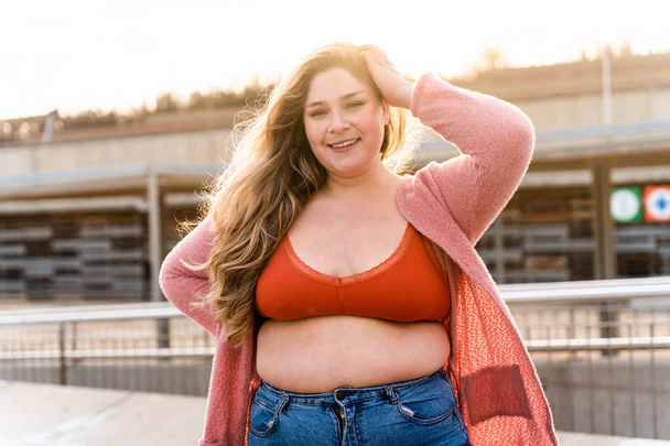 Beautiful and cheerful plus size young woman outdoors - Pretty overweight curvy female, concepts about femininity, women power, female emancipation, body positivity and body acceptance - Photo, image