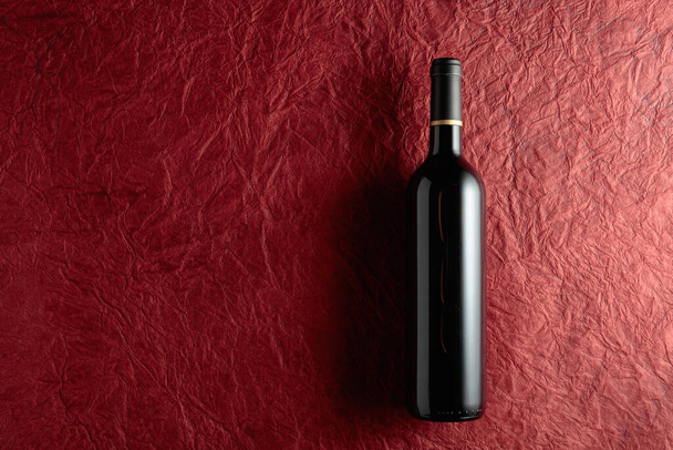 赤い紙の背景に赤ワインのボトル。トップ表示. - 写真・画像