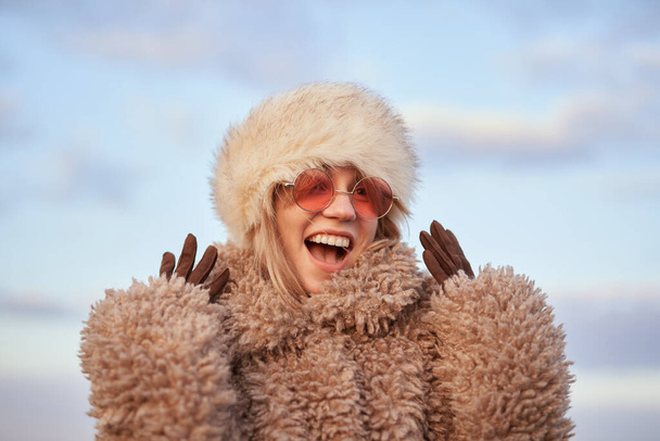Stylish happy girl portrait in artificial fur hat and coat outdoor - Photo, Image