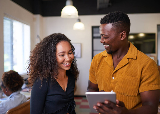 Un hombre negro le muestra a su colega una tableta digital y mira su reacción - Foto, Imagen