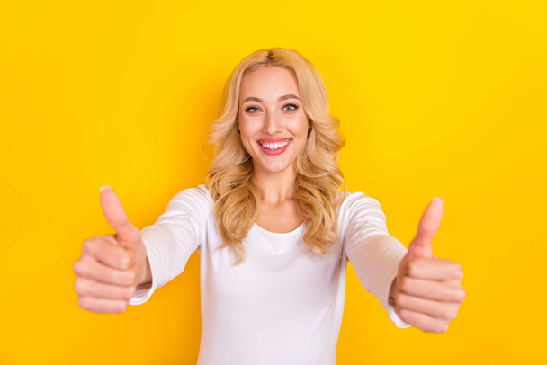 Photo of sweet excited young woman wear white shirt showing you two thumbs up isolated yellow color background - Foto, imagen