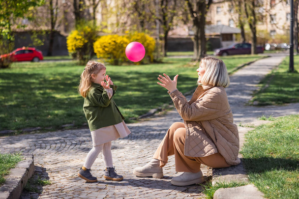 вид збоку щасливої матері і дитини, що грає з м'ячем у парку
 - Фото, зображення