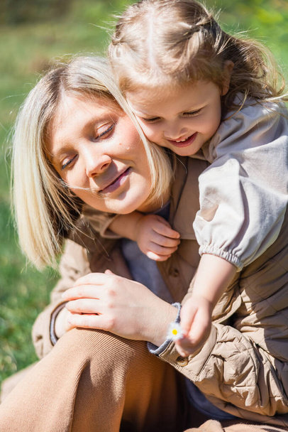 little child holding blurred flower near happy mom outdoors - Фото, изображение