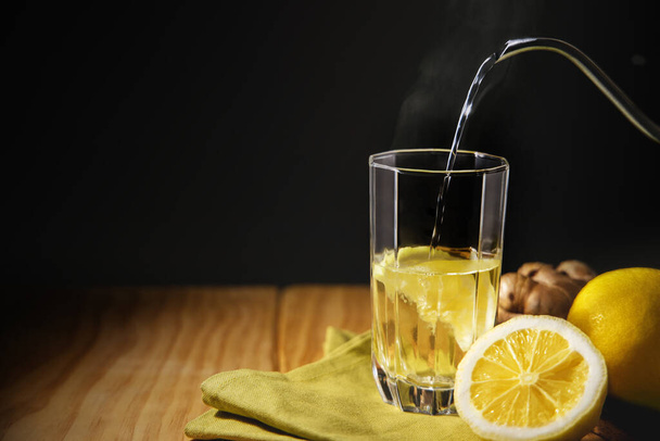 Sklenice horké infuze Ginger citrónový nápoj. Organický a zdravý životní styl. Čerstvá voda s citrónem. přítomen na stole s přirozeným světlem u okna. Sezónní nápoj.  - Fotografie, Obrázek