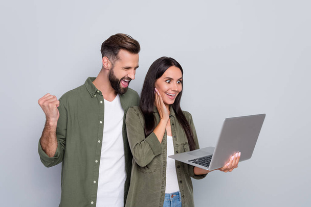 Portrait of attractive successful cheerful couple using laptop having fun rejoicing isolated over grey pastel color background - Fotoğraf, Görsel