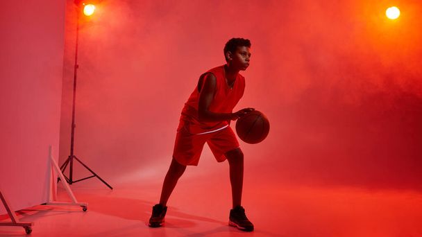 Boy basketball player with ball on red background - Фото, зображення