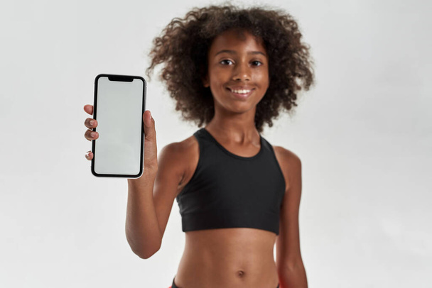 Cropped of smiling black girl show smartphone - Foto, afbeelding