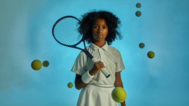 Tennis balls fly around black girl tennis player - Foto, imagen
