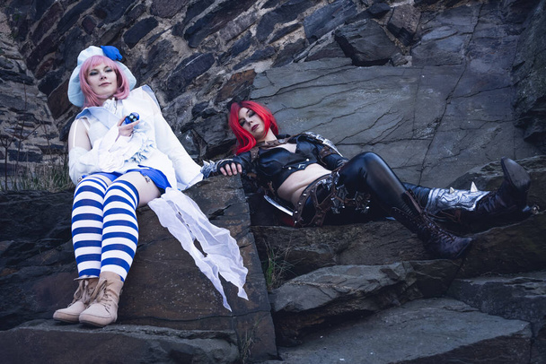 Two young female entertainers or performers in costume taking a break resting on rocks during performances - Foto, immagini